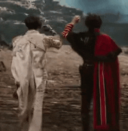 a man in a red cape is standing next to a man in a white coat .
