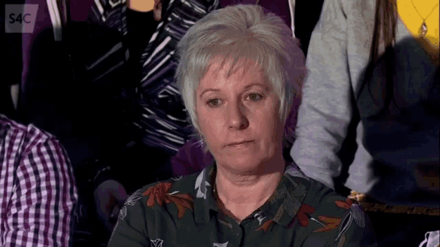 a woman sitting in a crowd with the letters s4c on the bottom