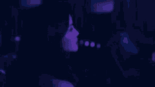 a woman is sitting in a chair in a dark room with purple lights behind her .