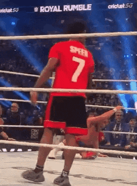 a man in a red shirt with the number 7 on it is in a wrestling ring .
