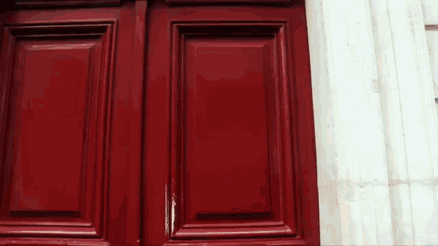 a close up of a red door with a white wall behind it