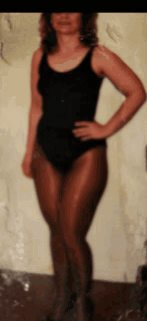 a woman in a black tank top and brown tights is standing with her hands on her hips