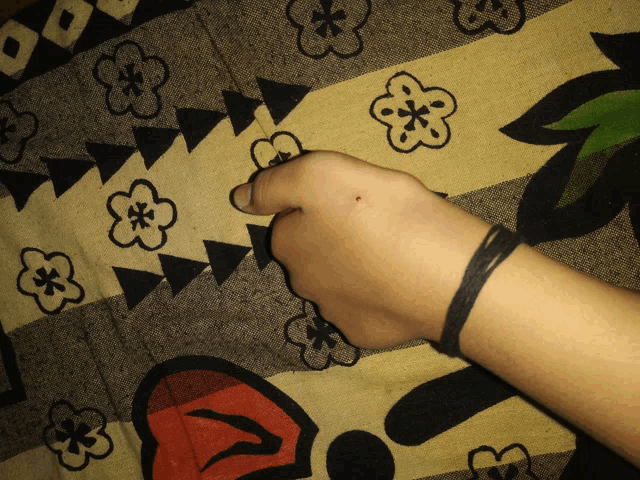 a person 's hand rests on a blanket with flowers and triangles