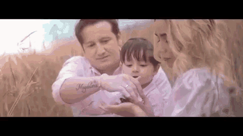 a man and a woman are holding a baby in a field .