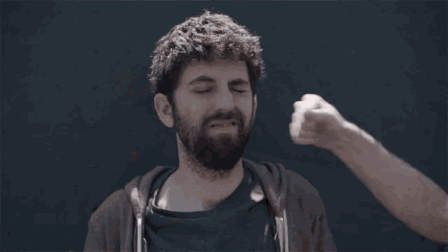 a man with a beard is smiling while another man looks on