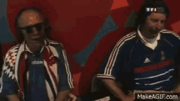 two men wearing headphones and adidas shirts are sitting in front of a red wall
