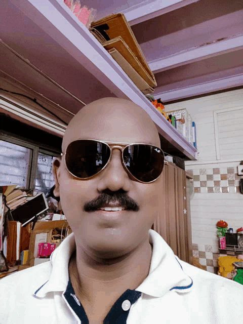 a man wearing sunglasses and a white shirt smiles for the camera