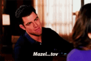 a man is talking to a woman and the words mazel..tov are on the screen