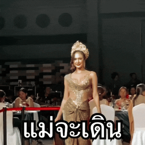 a woman in a gold dress with a crown on her head is walking down a runway in front of a crowd of people