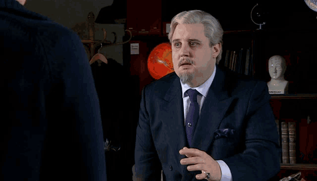 a man in a suit and tie talks to another man in front of a globe