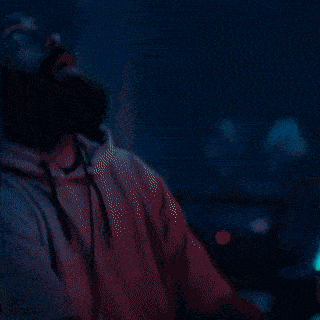 a bearded man wearing headphones and a hat looks up