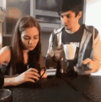 a man and a woman are sitting at a table with a cup of coffee .