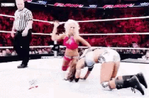 two women are wrestling in a wrestling ring with a referee watching .