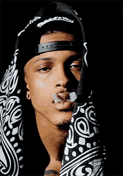 a man wearing a bandana is smoking a cigarette .