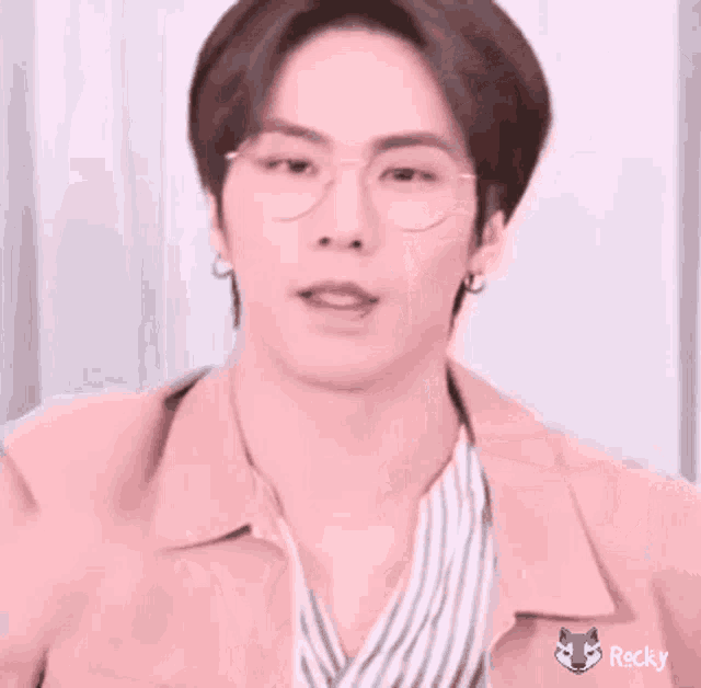 a young man wearing glasses and a pink jacket .