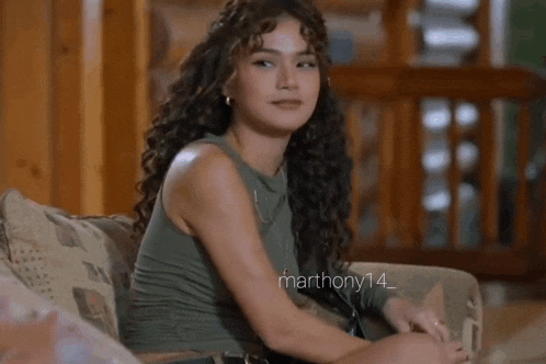 a woman is sitting on a couch with her legs crossed and looking at the camera .