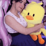 a woman is sitting in a pink chair holding a stuffed duck .