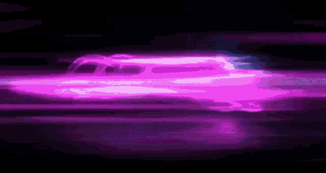 a purple car is driving down a dark street at night with a purple light coming out of it .