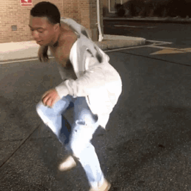 a man is dancing on the sidewalk in front of a building .