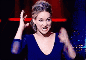 a woman in a blue shirt is making a funny face with her hands in the air