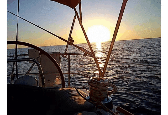 the sun is setting behind the steering wheel of the boat