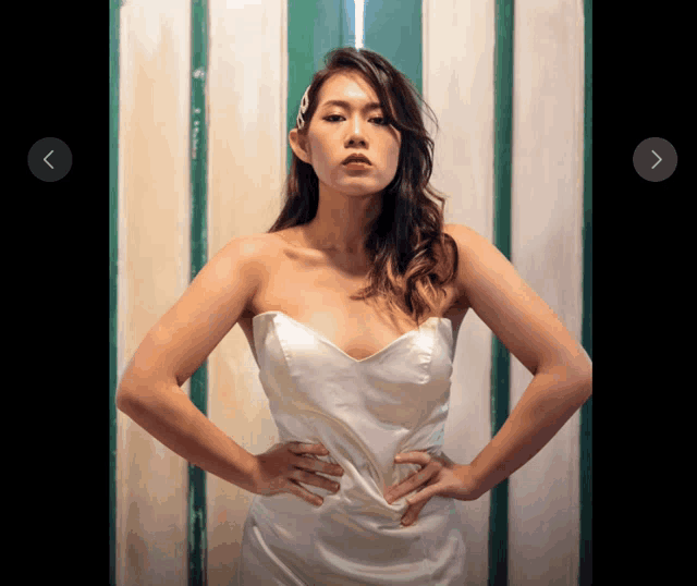 a woman in a white dress stands with her hands on her hips in front of a green and white wall
