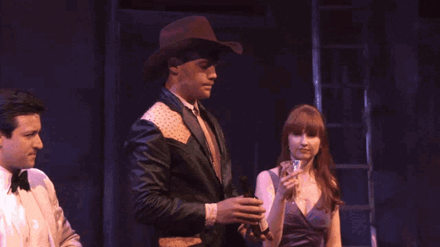 a man in a cowboy hat is standing next to a woman holding a martini and the words god bless america are visible