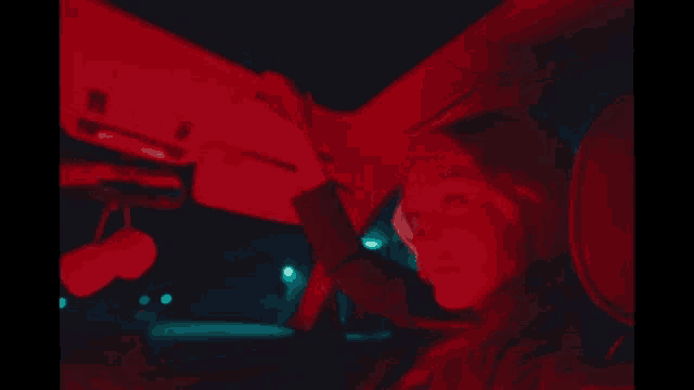 a woman is sitting in the back seat of a car with red lights behind her .