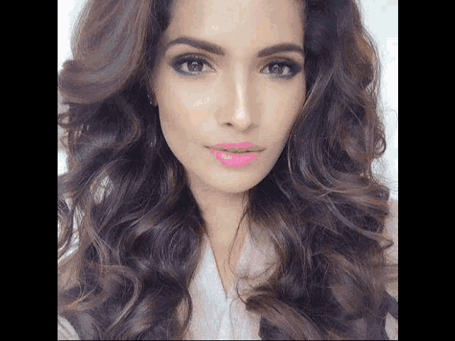 a close up of a woman 's face with long curly hair and pink lipstick .