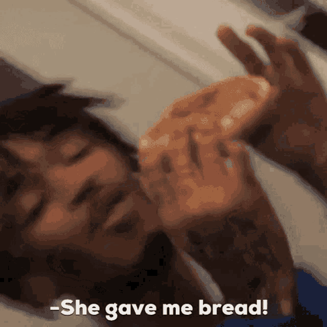 a man is eating a slice of pizza and saying she gave me bread .