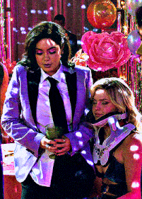 a woman in a tuxedo is holding a glass of wine next to a woman with a broken neck .