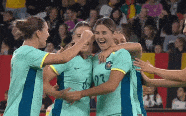 a group of female soccer players are hugging each other and one has the number 23 on her shirt