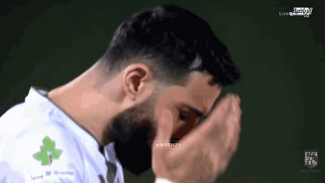 a man with a beard wearing a white shirt with a green flower on the front