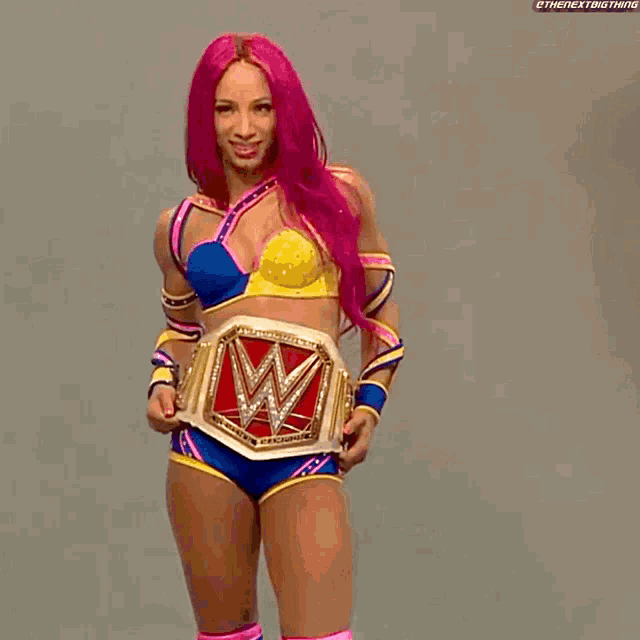 a woman with pink hair is holding a wrestling belt with a w on it