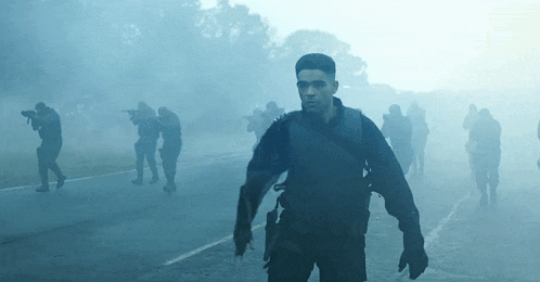 a group of soldiers are walking down a road in a foggy scene