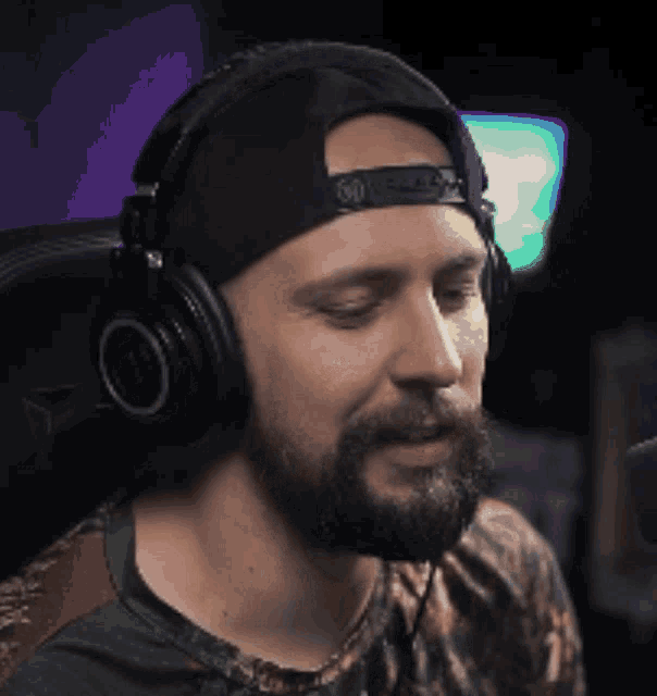 a man with a beard is wearing headphones and a baseball cap