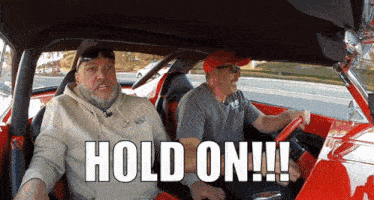 two men sitting in a red car with the words hold on written on the screen