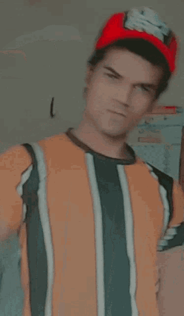 a man wearing a striped shirt and a red hat is flexing his muscles