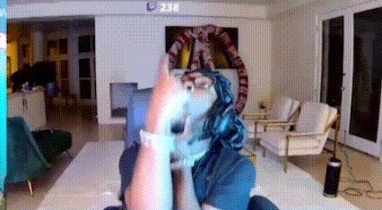 a person is sitting on a couch in a living room with a snake hanging from the ceiling .