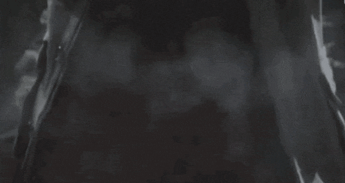 a black and white photo of a person standing in the dark with smoke coming out of their mouth .