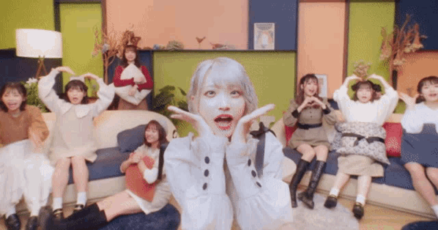 a group of young women are sitting on a couch and making heart shapes with their hands