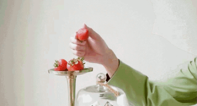 a young man is holding a strawberry in his hand and eating it .