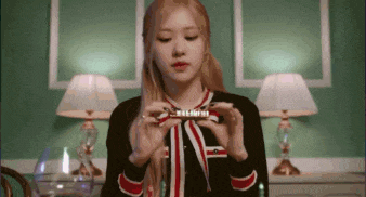 a woman in a black and red sweater is holding a piece of chocolate .