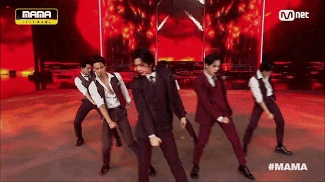 a group of men in suits are dancing on a stage in front of a mama logo