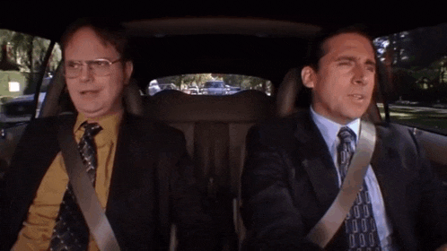 two men in suits are sitting in a car and one of them is saying " i am planning a bomb scare