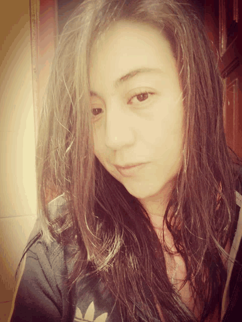 a girl with long hair is wearing a black adidas jacket