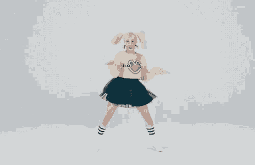 a girl wearing a yellow sweater with a heart on it and a blue skirt is dancing .