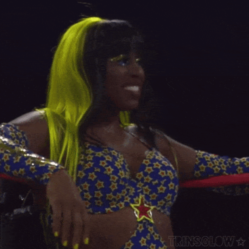 a woman in a wrestling ring is wearing a blue and yellow top with stars