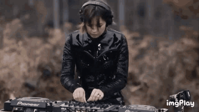 a woman wearing headphones is playing music on a pioneer dj mixer .