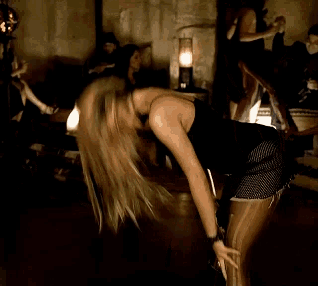 a woman in a black top and shorts is dancing
